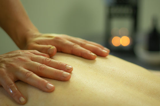 Terapeut utför lugnande massage med händer mot kundens rygg.